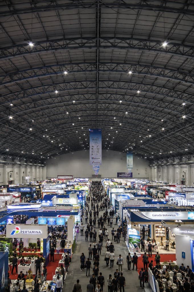 Large-scale Indonesian convention and exhibition hall with crowds and branded booths from elevated view
